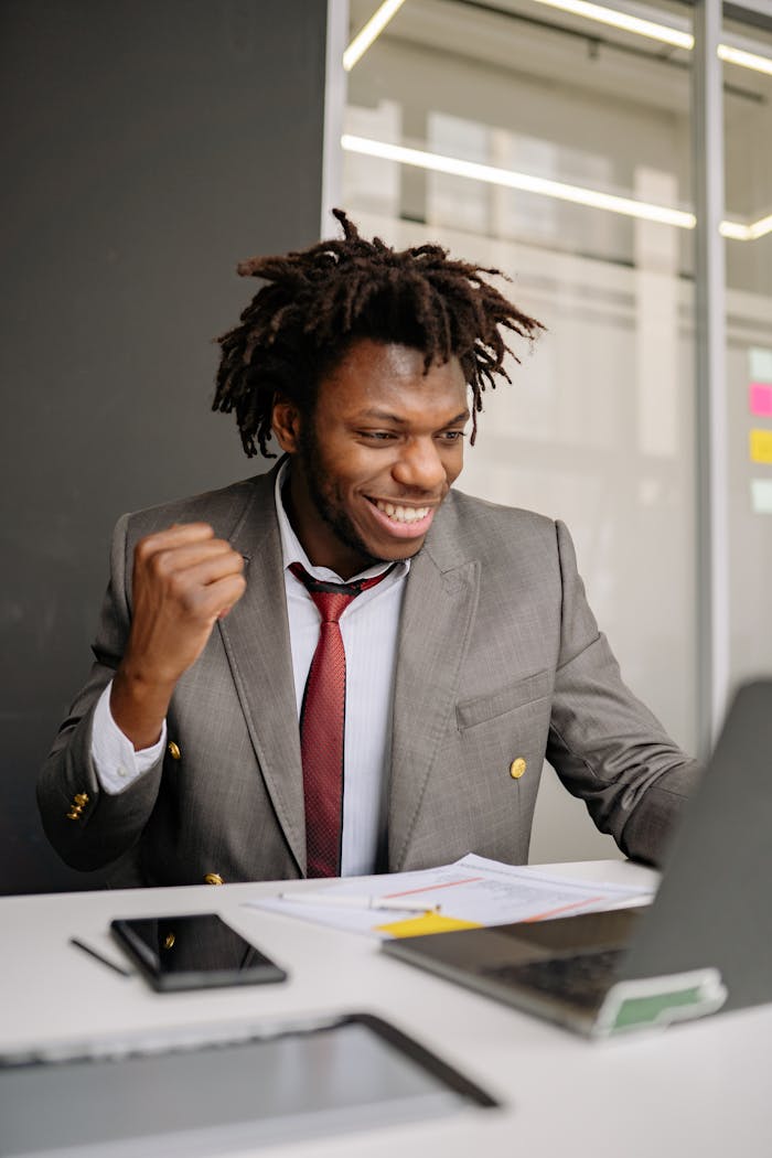 The Art of Drawing Readers In: Your attractive post title goes here Excited businessman in suit celebrating success at his desk indoors.